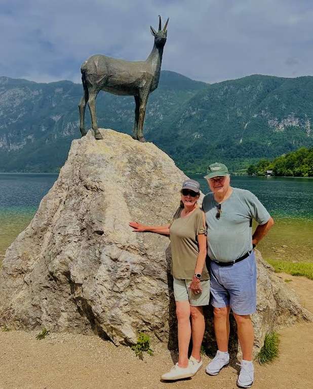 Robin and Paul li front of a rock and a statue of a deer at Lake Bohinj in Slovenia